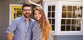 Young couple in front of their new house.